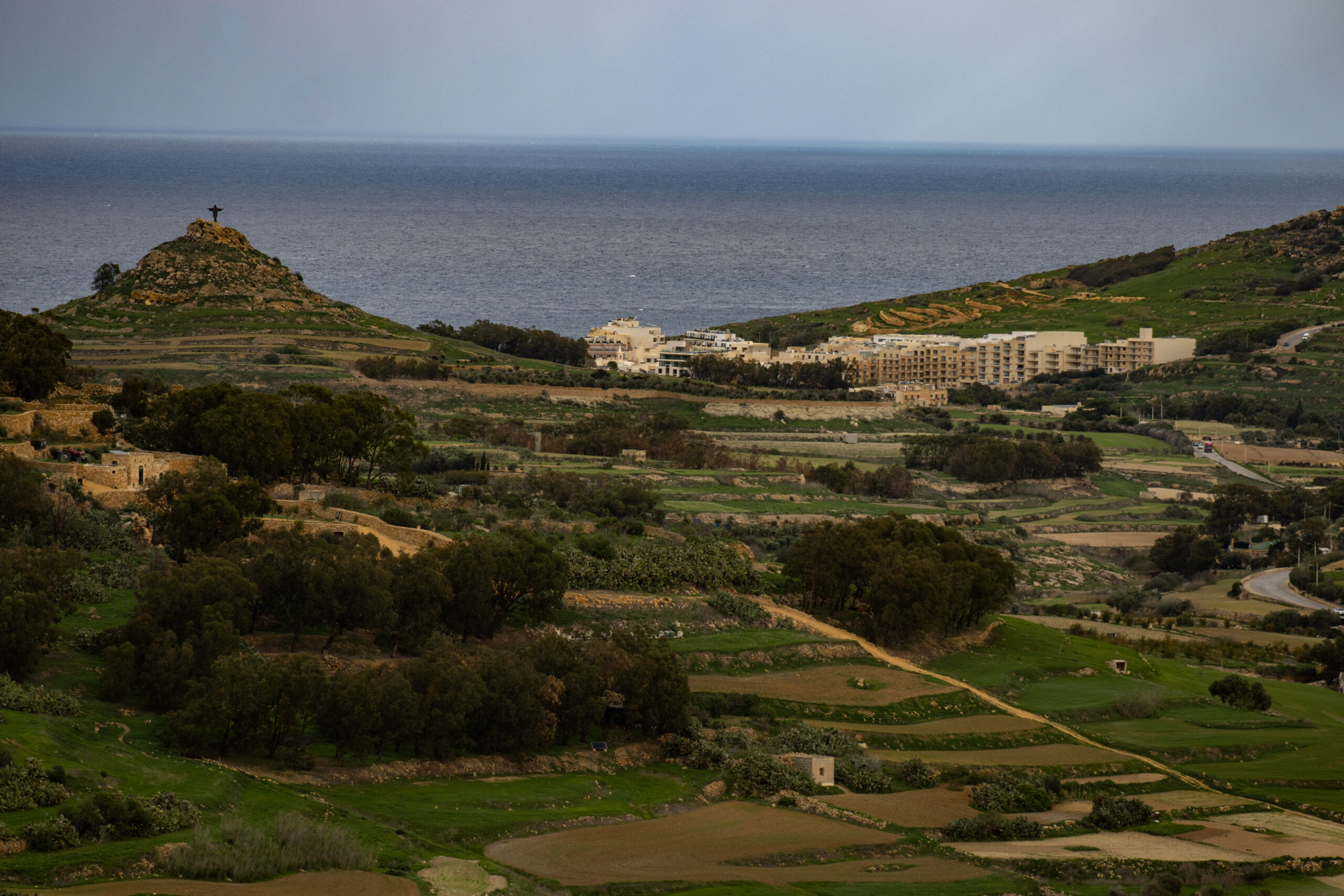 A view of Gozo featuring green fields and distant sea views